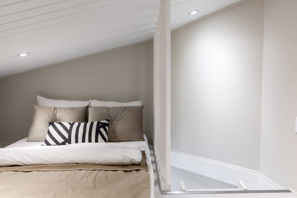 Loft med säng och målade väggar i neutral ton.